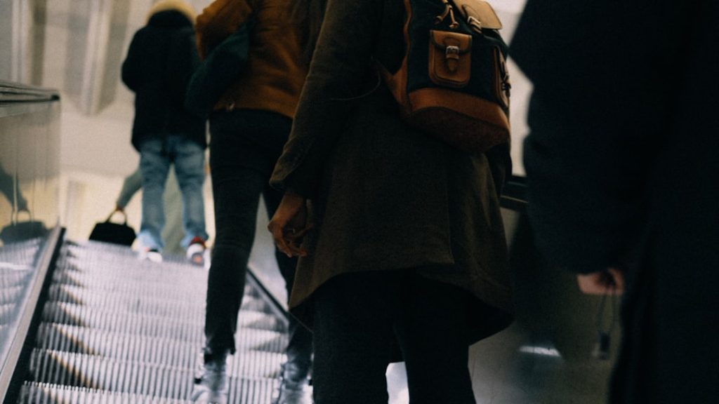 a-group-of-people-walking-down-an-escalator-4kphwthpewu