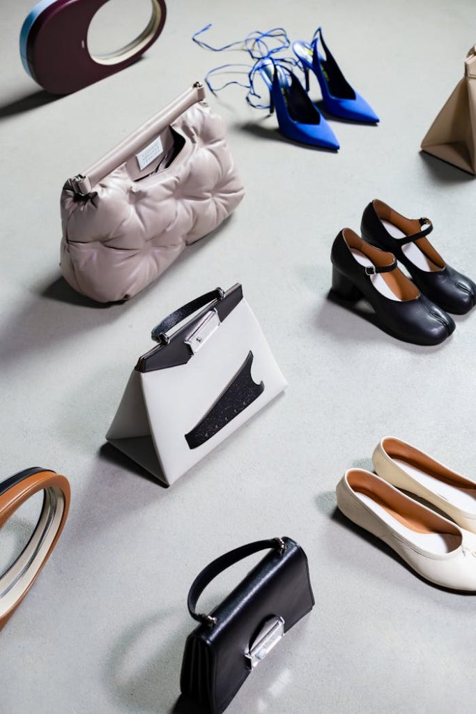 High-angled shot of stylish shoes and bags arranged on a white surface, exuding elegance and luxury.